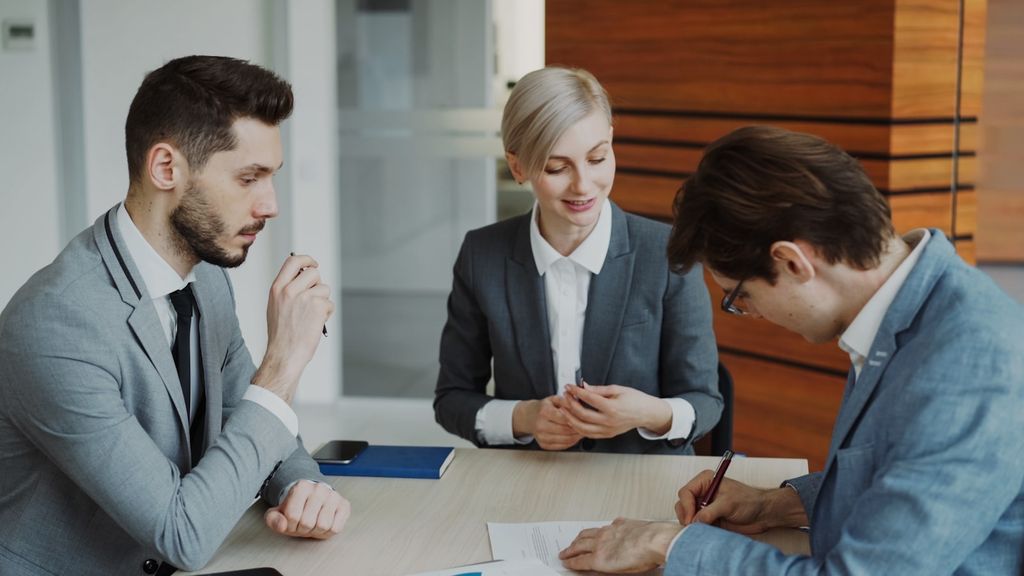Business professionals signing a contract at a table
